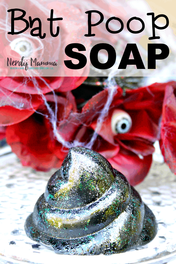 black and glitter soap in the shape of a poop in front of roses with eyeballs in the center covered in cobwebs