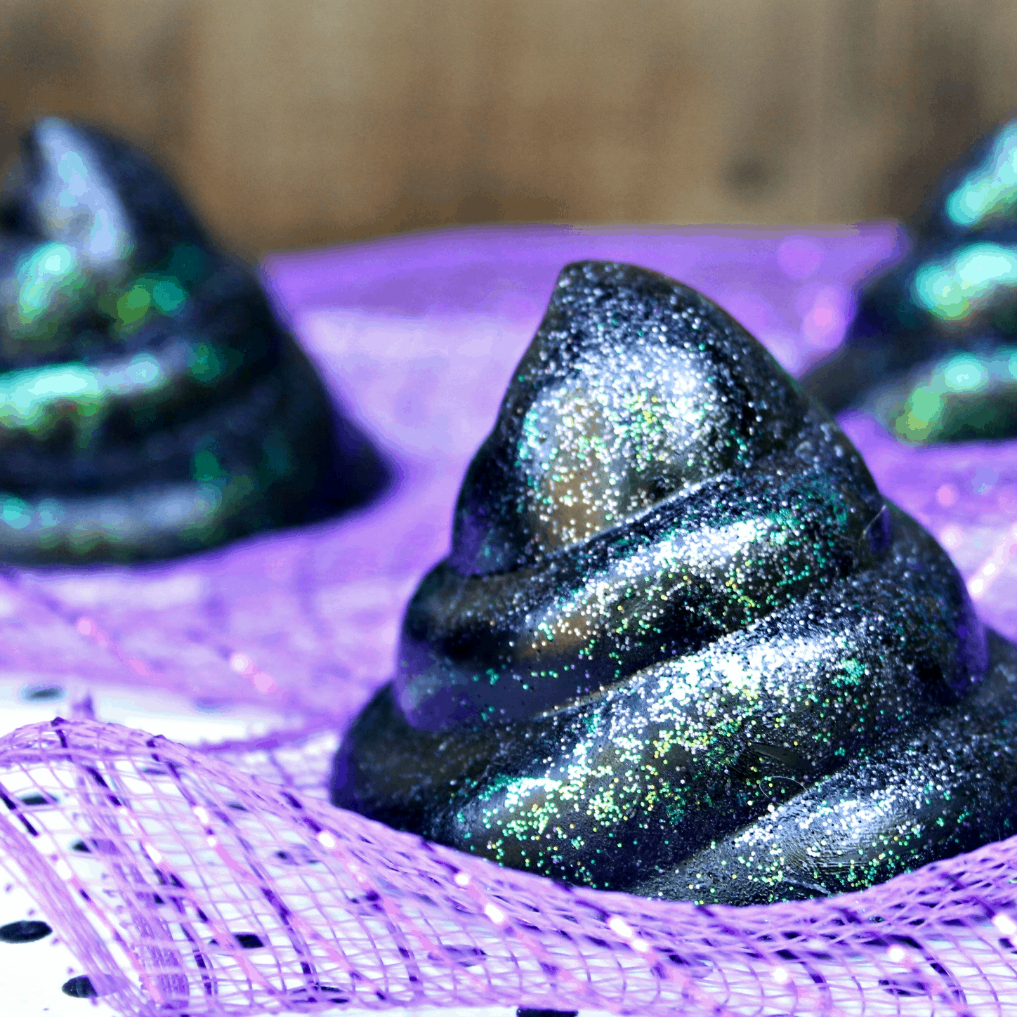 black and glitter soap in the shape of a poop on a purple cloth