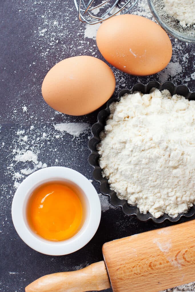 overhead view of a table prepped with eggs, egg yolk and flour to bake with eggs