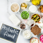 Super healthy probiotic fermented food sources, drinks, ingredients, on white marble background copy space top view.