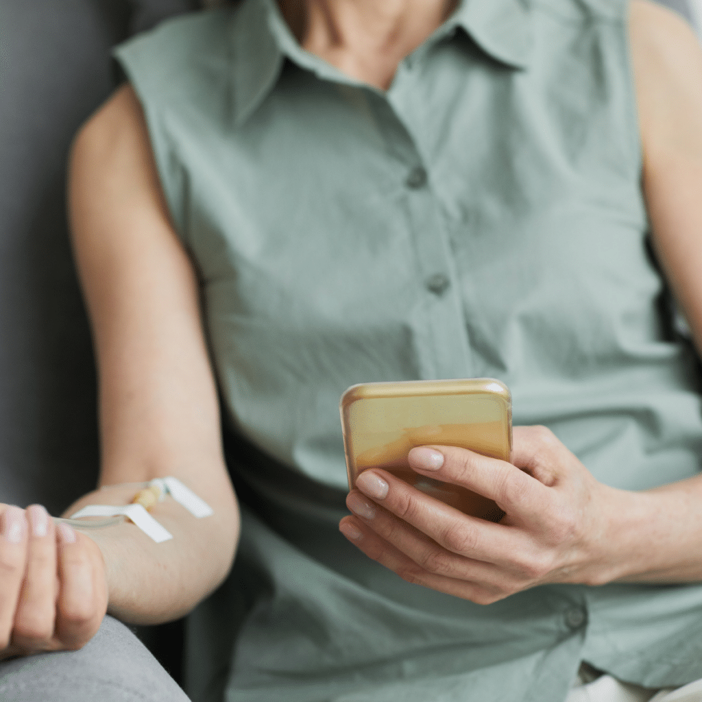 Minimal close up of unrecognizable woman getting IV drip and using smartphone