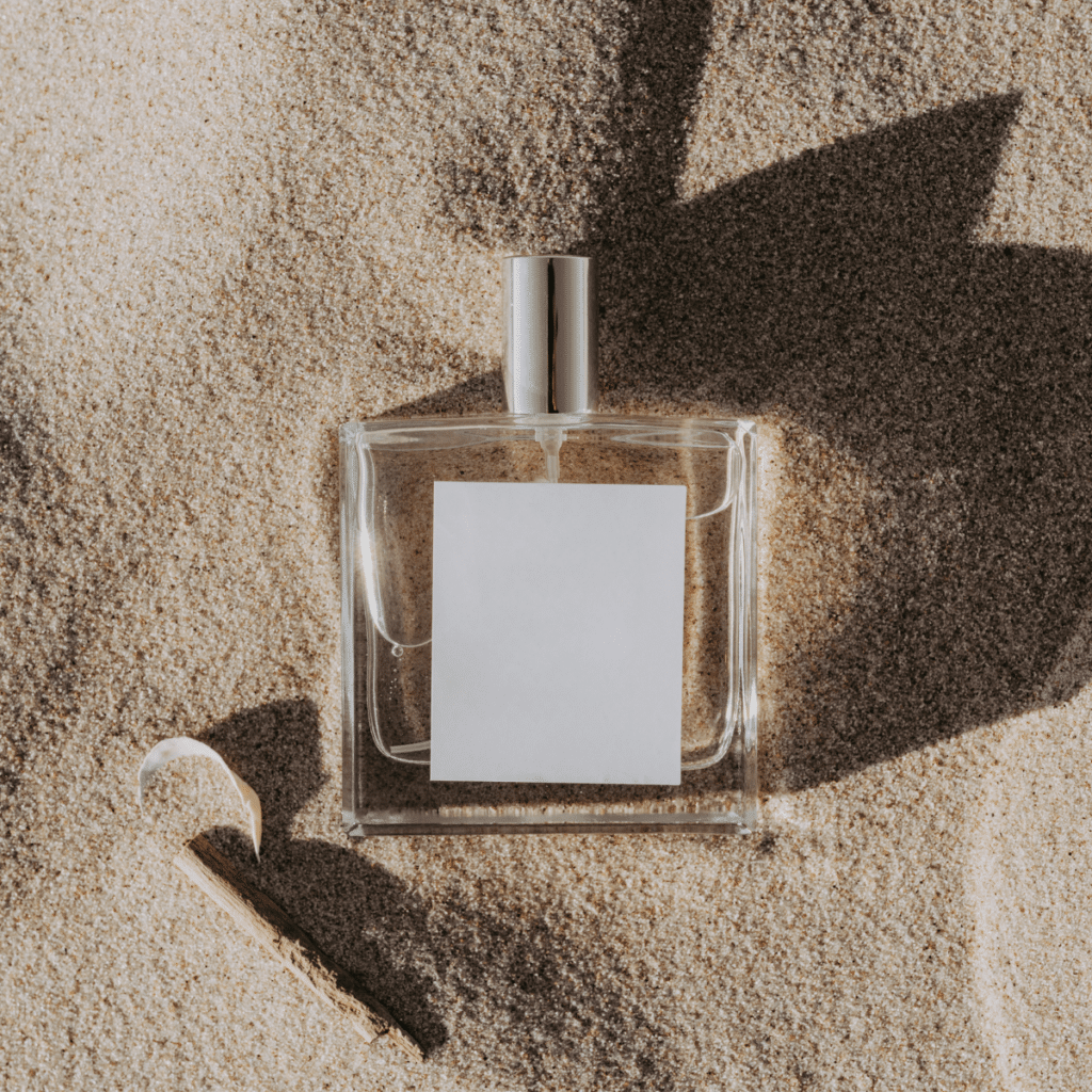 Clear glass perfume bottle on a white sand