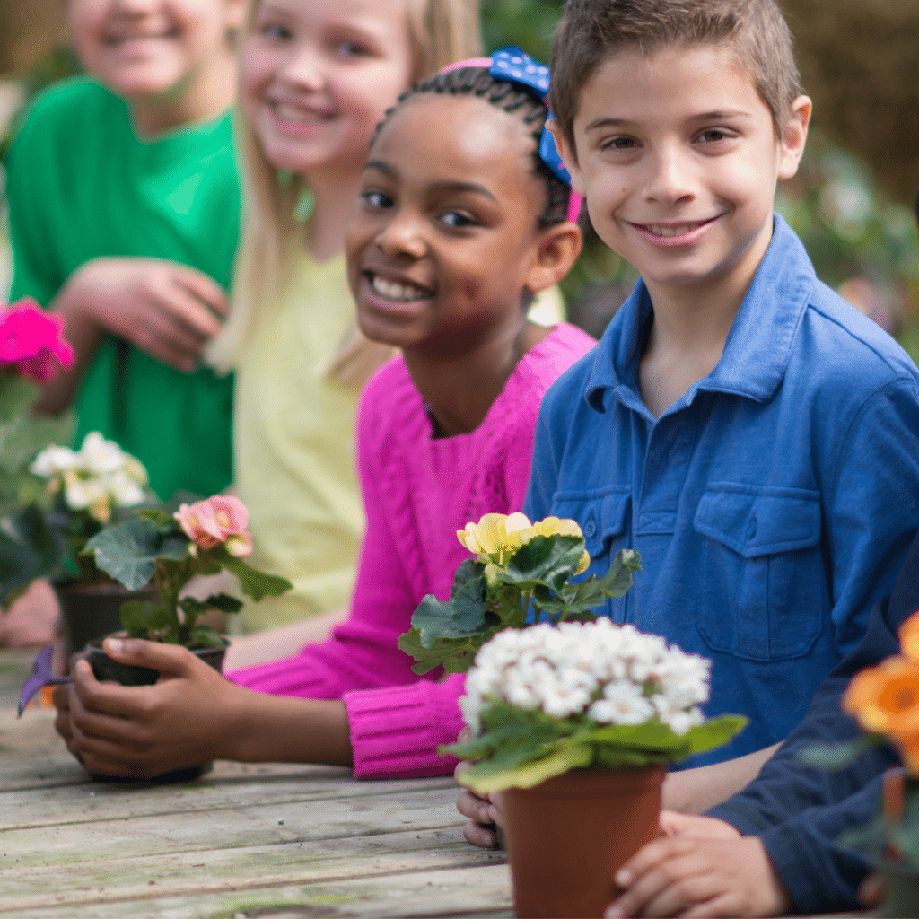 A multi-ethnic group of elementary age students are picking out plants together in a nursery on a school.