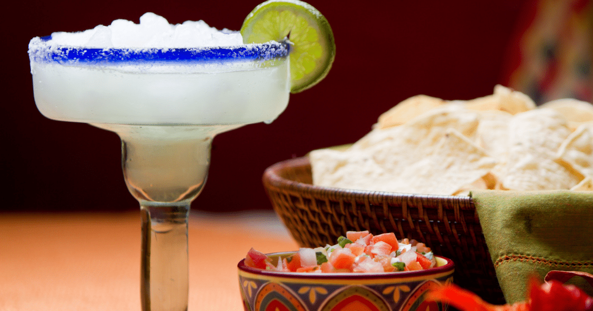 Traditional Mexican chips, salsa and frozen margarita with salt and lime on the rim of the glass on a table