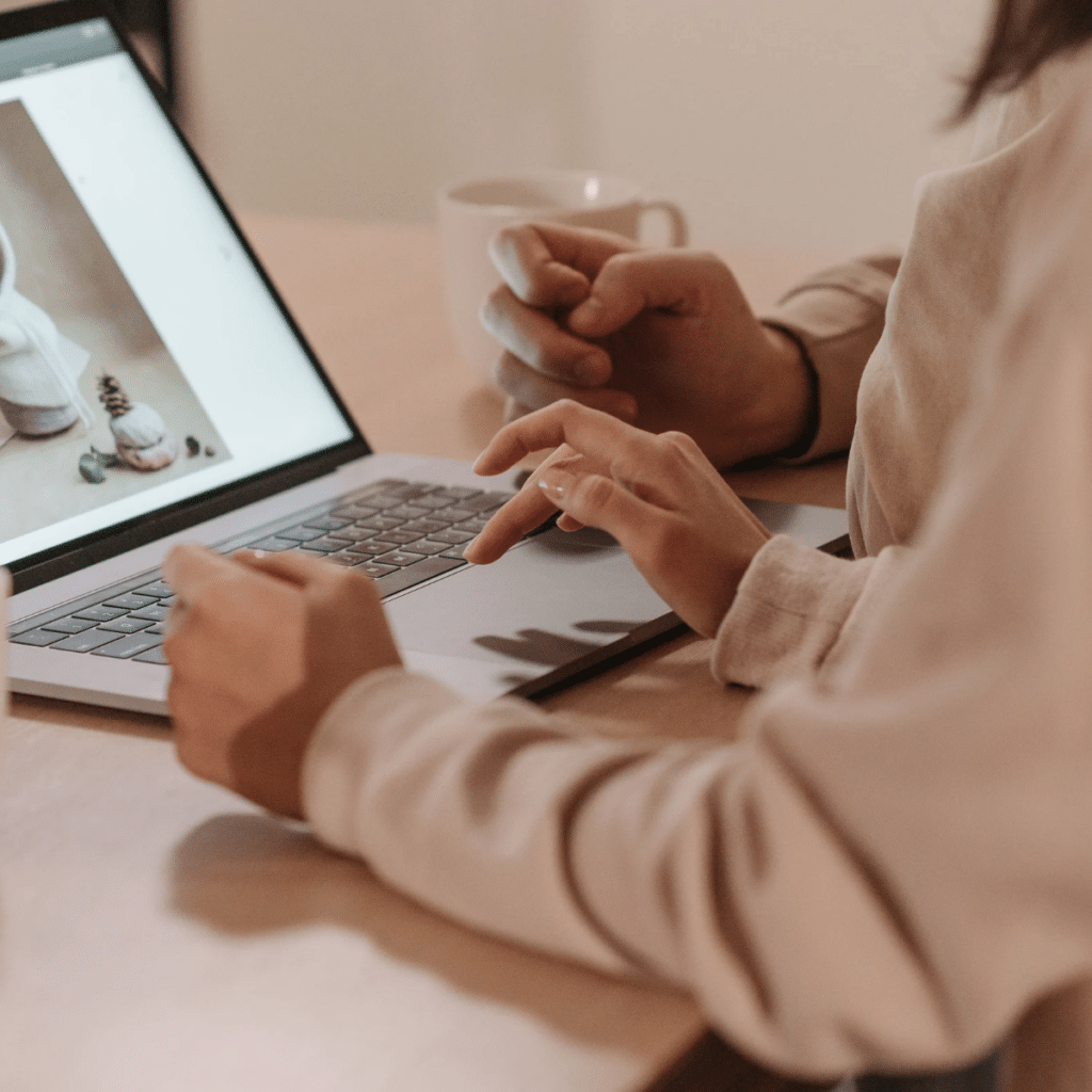 A person using a laptop wearing a sweashirt