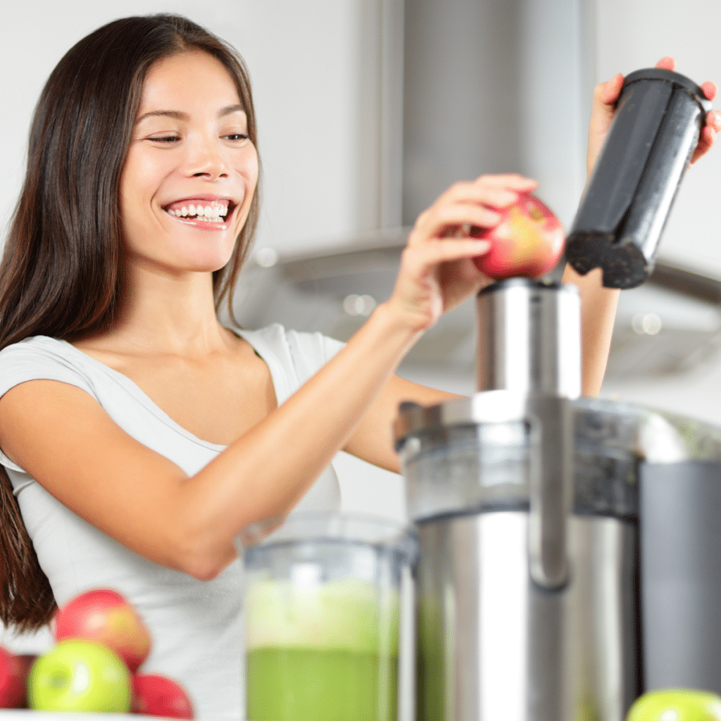 A woman making an apple and green vegetable juice using a juicer machine at home in kitchen