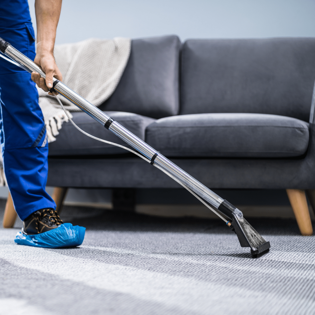Photo of janitor cleaning carpet with vacuum cleaner