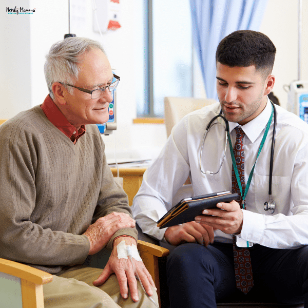 A doctor shows an elderly patient medical information on a tablet during a stem cell treatment consultation.