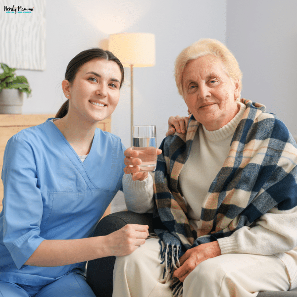 A caregiver provides non-medical senior home care by assisting an elderly woman in a cozy living room, illustrating one side of the home care vs. home health care comparison.