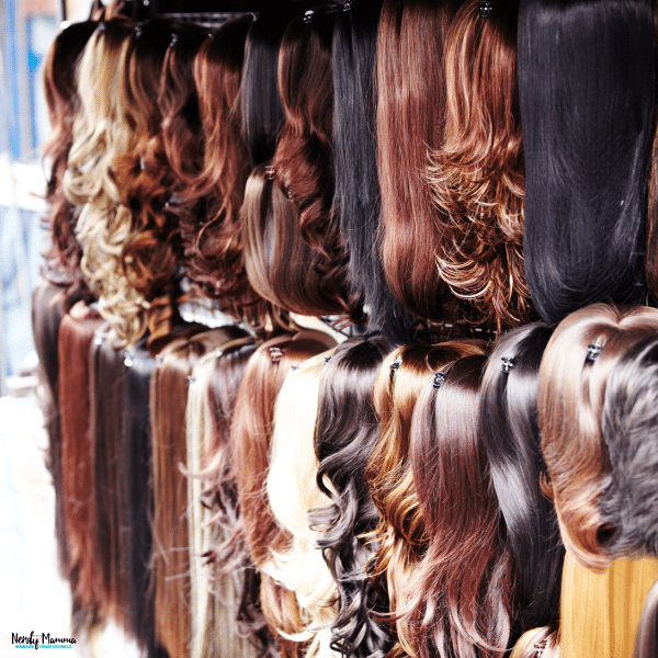 A variety of lace wigs in different colors and styles displayed on a shop wall, showcasing everyday hair solution options.