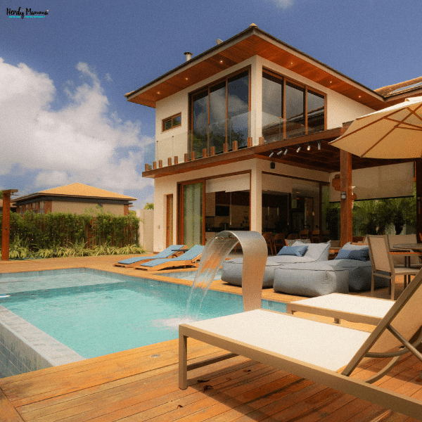 Modern backyard swimming pool with clear blue water, lounge chairs, and a waterfall feature, highlighting proper pool care and maintenance.