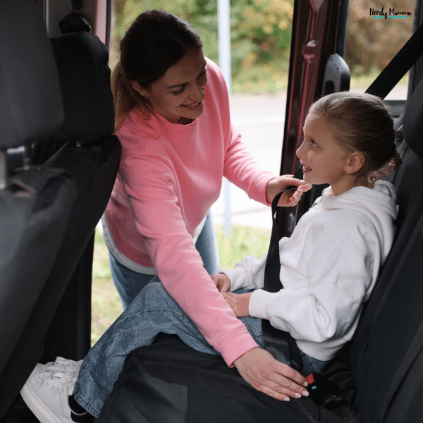 Mother fastening her child’s seatbelt in the back seat of a car to prepare safely for travel and unexpected roadside situations.