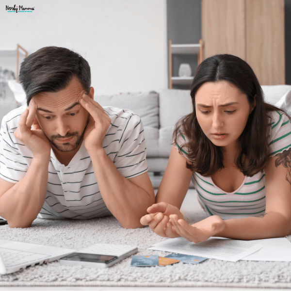 Parents look overwhelmed as they review bills on the floor, illustrating the emotional stress of sudden financial emergencies.