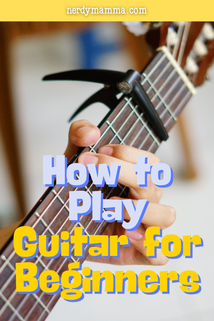 Close-up of fingers pressing guitar strings with a capo, representing beginner guitar techniques and chord practice.