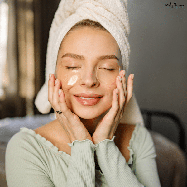 Woman relaxing with under-eye patches and a towel wrap, representing healthy skincare habits and self-care beauty routines.