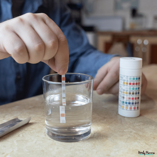 Person testing household water with a water quality strip to check for hard water minerals and buildup concerns.