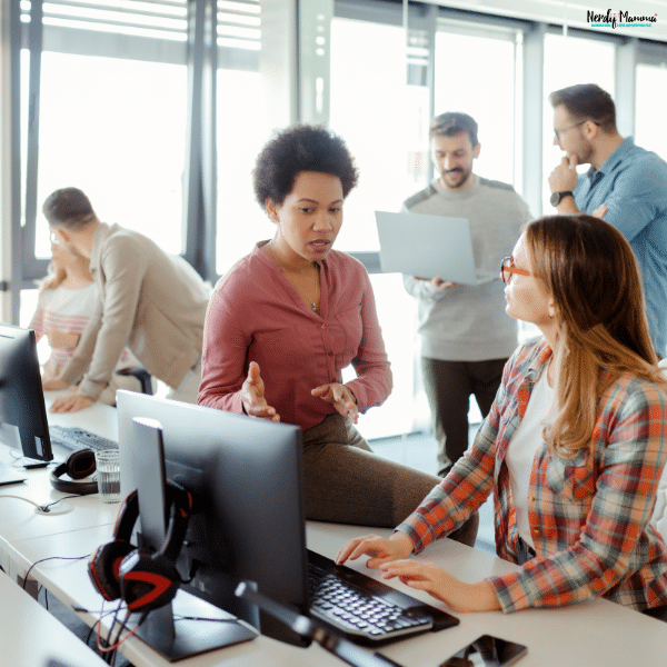 Office team members collaborating at computer workstations, representing workplace wellness programs, employee engagement, and healthy work culture.