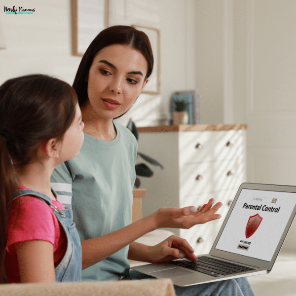 Mother teaching her daughter about online safety settings and digital protection tools on a laptop at home.