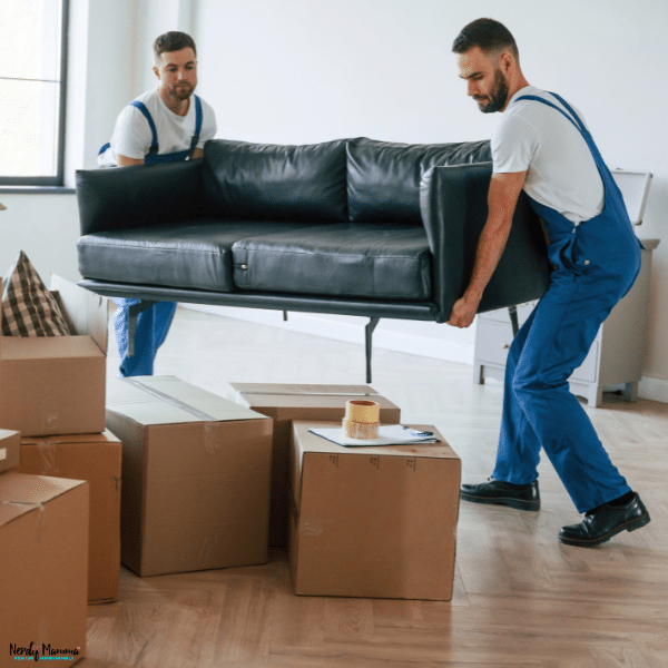 Professional movers carrying a black sofa through a home during a family relocation and moving service comparison.