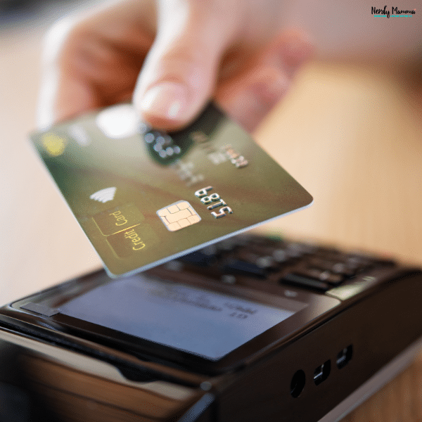 Person tapping a credit card on a payment terminal, representing smart credit card application timing and financial planning strategies.