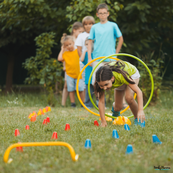 Children complete a backyard obstacle course with hoops, cones, and movement challenges that encourage active outdoor play.