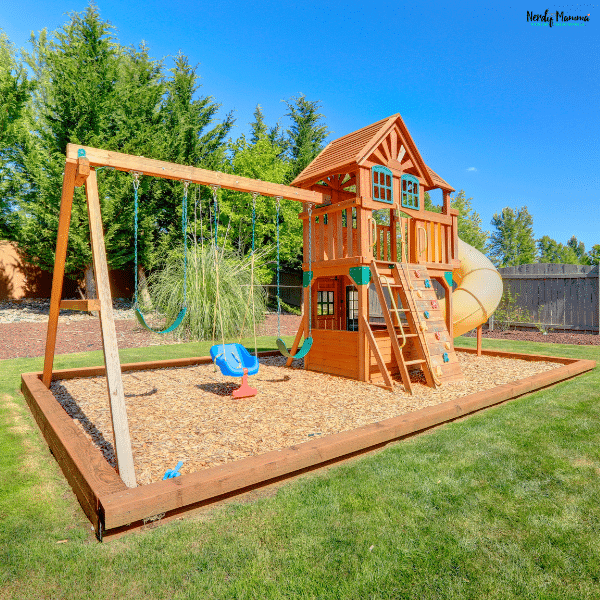 Large wooden backyard playground set with swings, climbing wall, clubhouse, and slide designed for active outdoor play.