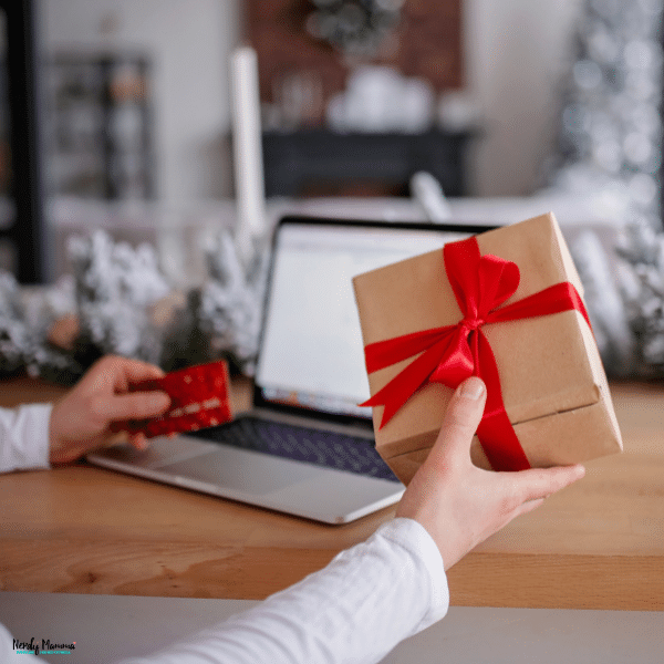 Person holding a wrapped gift while shopping online, highlighting personalized gifting and thoughtful gift selection.