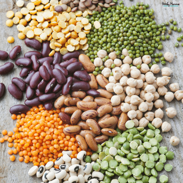 Assorted dried beans and legumes arranged on a wooden surface to represent different bean varieties used for cooking and food storage.