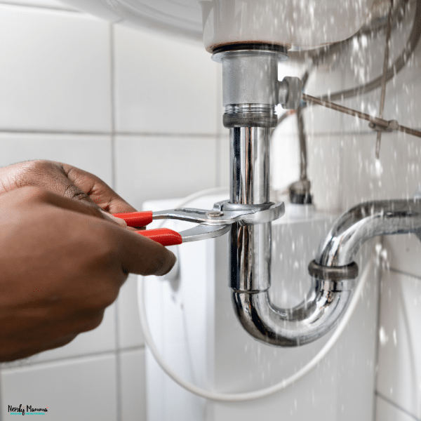 Person tightening a leaking sink drain pipe, highlighting plumbing repairs and the importance of quality workmanship.