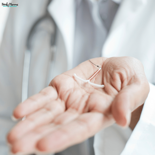 Healthcare professional holding an IUD before a contraceptive consultation in a clinical setting.