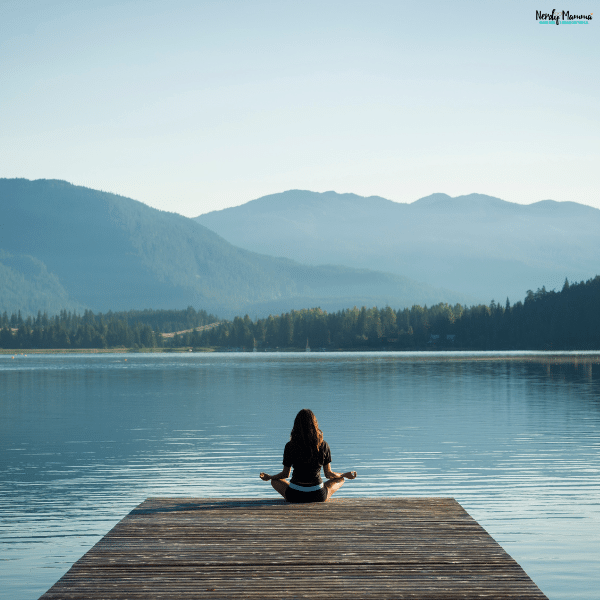 Person practicing meditation in a peaceful outdoor setting as part of a self-improvement routine focused on mindfulness and personal growth.