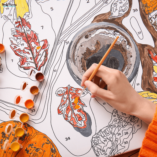 Person painting a personalized craft project on canvas, creating a unique handmade keepsake for meaningful family memories.