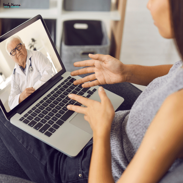 A woman speaks with a healthcare provider during a virtual medical appointment on a laptop from the comfort of her home.