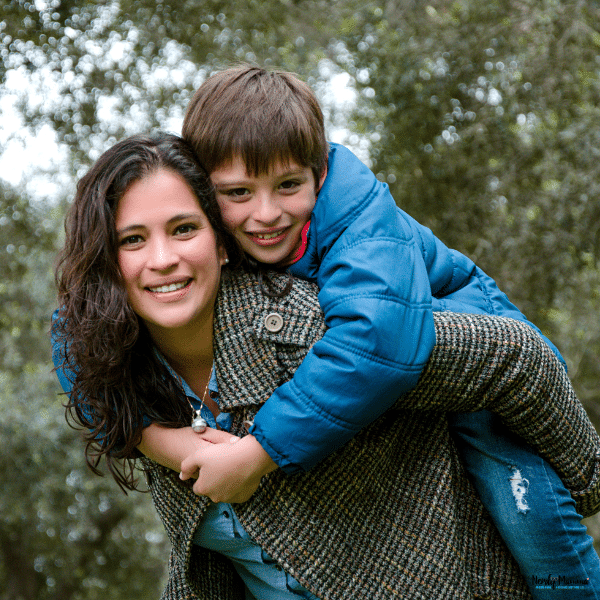 Parent gives an older child a piggyback ride outdoors while keeping a balanced posture to reduce strain on the back.