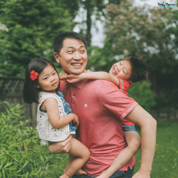 Parent carrying two young children outdoors, showing safe and practical ways to transport children during family activities.