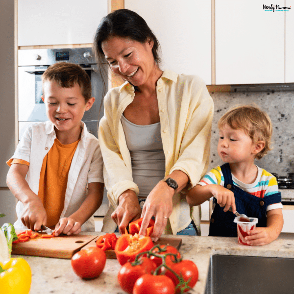 Parent preparing a healthy family meal with young children helping in the kitchen during a busy weekday.