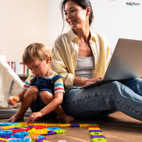 Mother working on a laptop while caring for her young child, showing how parents can balance earning an income and family responsibilities.