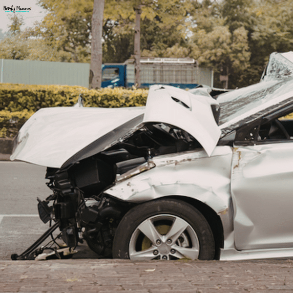 A severely damaged car with a crushed front end sits on the roadside after a traffic accident.