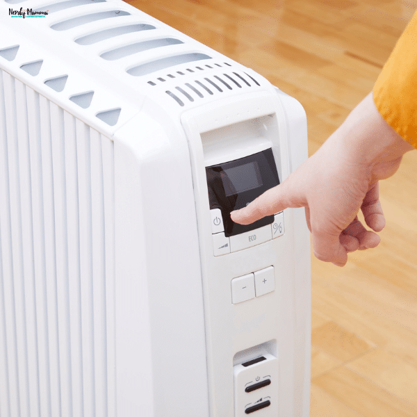Hand adjusting the digital controls on an energy-efficient electric storage heater to improve home heating and energy savings.