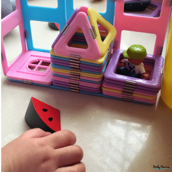 Child building a colorful structure with magnetic tiles, encouraging creative play, fine motor skills, and problem-solving.