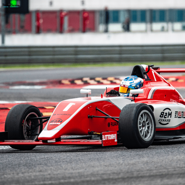 An open-wheel race car speeds through a corner, representing driver performance monitoring during a competitive track session.