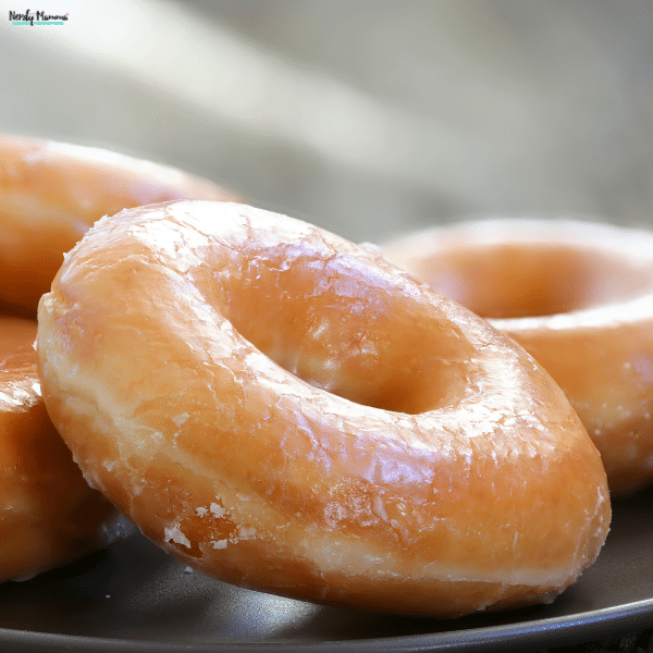 A close-up of homemade Amish glazed donuts with golden-brown edges and a shiny, sweet sugar glaze.