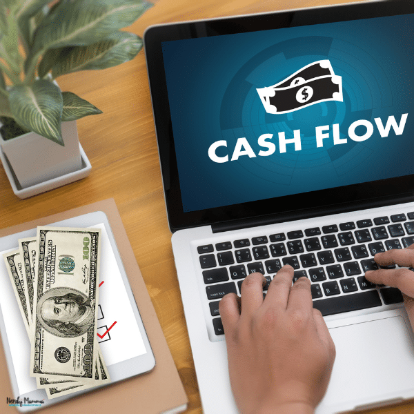 Hands using a laptop beside cash and budgeting materials, representing household cash flow management and practical ways Michigan families can track expenses and save money.