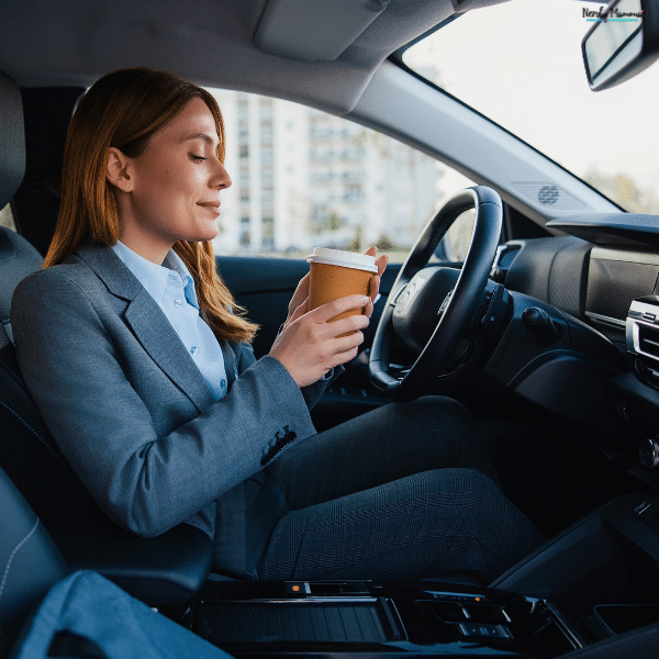 Woman sitting in the driver’s seat with a coffee cup, representing everyday commuting and transportation expenses for Michigan families.