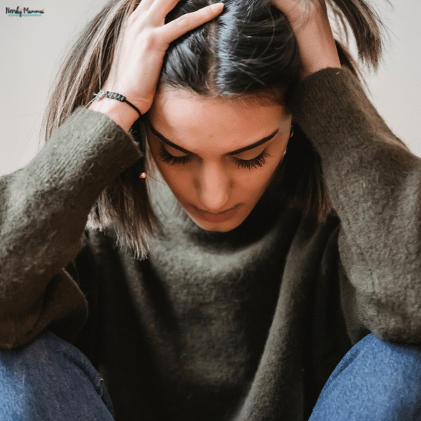 A person sitting with their head in their hands, illustrating emotional stress, anxiety, and mental fatigue.
