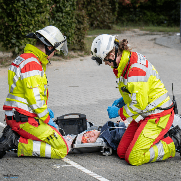 Emergency responders provide medical care to an injured person lying on the ground after an accident, showing the immediate impact of a serious injury.