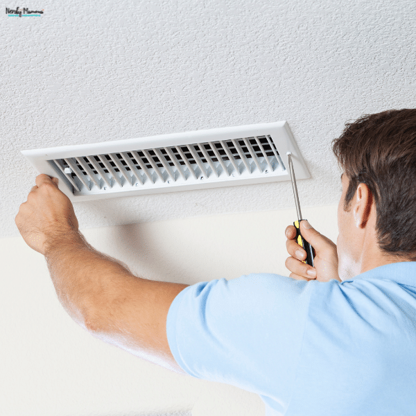 A technician removes a ceiling vent cover to begin a professional air duct cleaning service in a residential HVAC system.