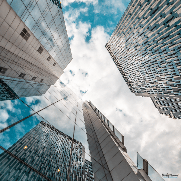 Glass office towers rise toward a cloudy sky, representing properties that cost segregation companies may assess for tax savings.