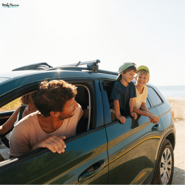 A family leans out of their vehicle during a road trip stop near the beach, enjoying a break together during their drive.