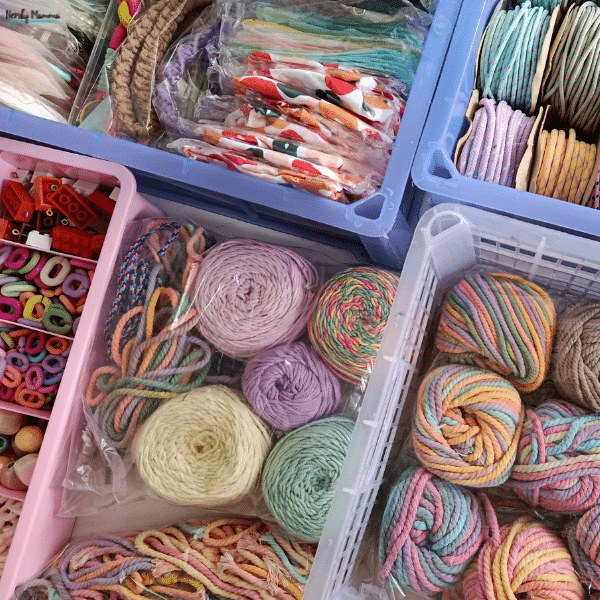 Colorful yarn, cords, beads, and assorted craft supplies organized in small storage bins to keep a craft stash contained and tidy.